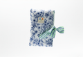 The Blue Toile & Striped Ribbon Quilted Book Sleeve featuring a blue pastoral toile print on cotton fabric, designed with a vertical blue and white ticking stripe accent band, vertical channel quilting, a gold top zipper, a side hand strap, and a centered white KIALIYAH label.