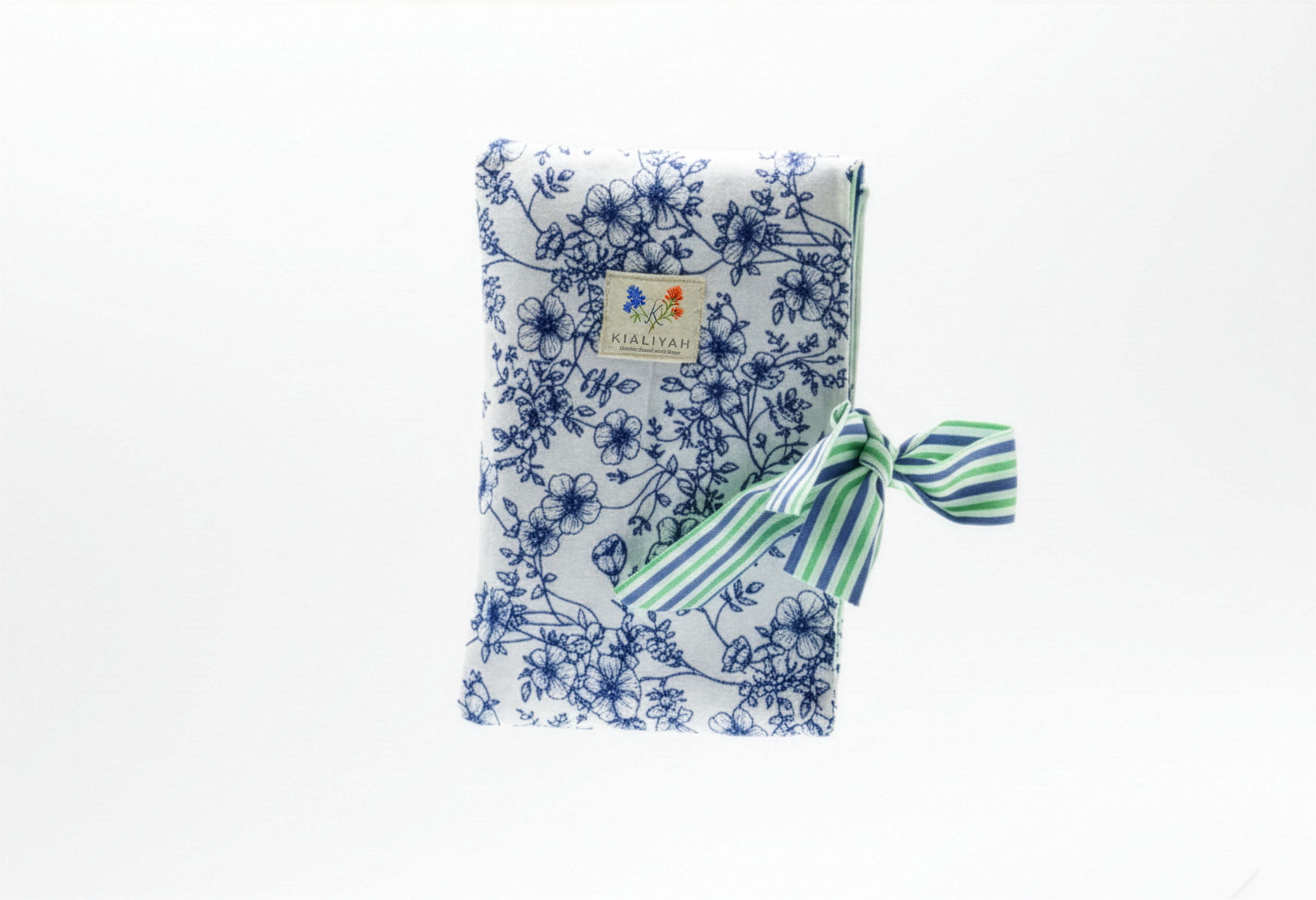 The Blue Toile & Striped Ribbon Quilted Book Sleeve featuring a blue pastoral toile print on cotton fabric, designed with a vertical blue and white ticking stripe accent band, vertical channel quilting, a gold top zipper, a side hand strap, and a centered white KIALIYAH label.