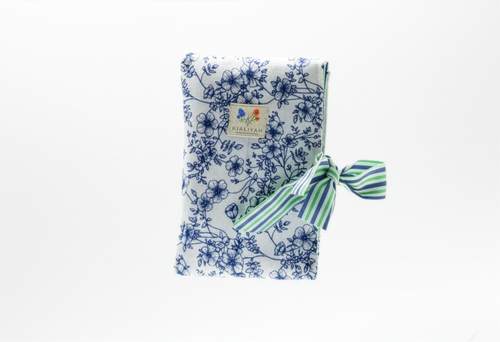 The Blue Toile & Striped Ribbon Quilted Book Sleeve featuring a blue pastoral toile print on cotton fabric, designed with a vertical blue and white ticking stripe accent band, vertical channel quilting, a gold top zipper, a side hand strap, and a centered white KIALIYAH label.