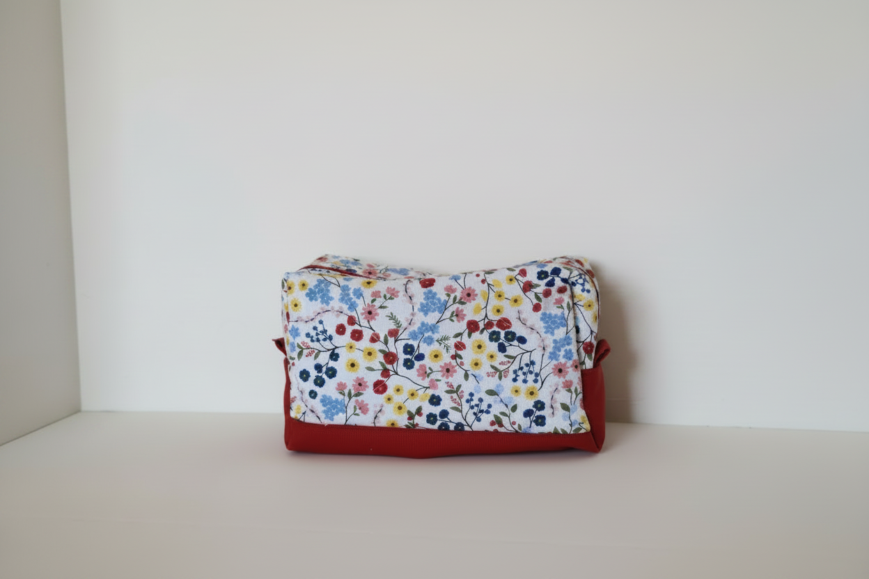 Floral-patterned pouch with a red border on a white surface