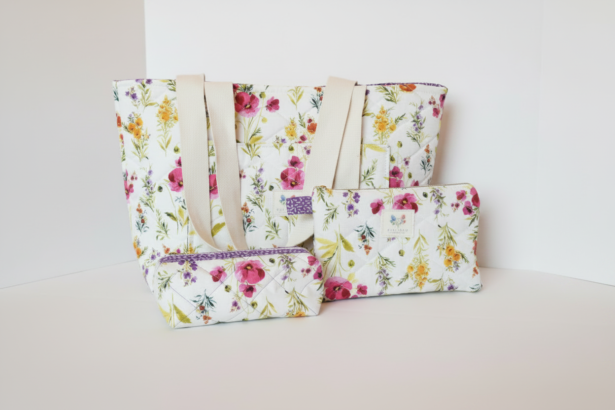 Wildflower Garden Quilted Travel Bundle featuring a matching white canvas tote bag with magenta and yellow flowers, a boxy cosmetic case, and a flat wallet pouch against a clean white background.