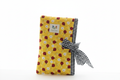 Handmade yellow ladybug print quilted book sleeve with black and white gingham border and large fabric bow.