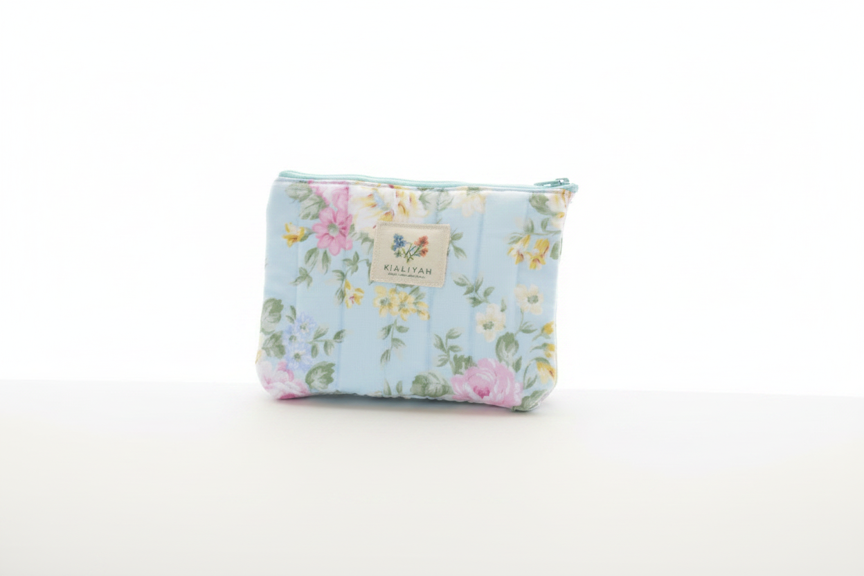 English Rose quilted canvas wallet pouch with a light blue and pink rose floral pattern, matching mint zipper closure, and a central fabric brand label against a clean white background.