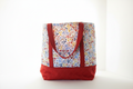 Handmade large quilted beach tote bag featuring a colorful wildflower print fabric top and a structured crimson red diamond-quilted base with red straps.