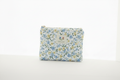 Handmade bluebell print quilted mini wallet with blue and yellow wildflowers, artisan fabric card holder with vertical quilting and gold zipper.