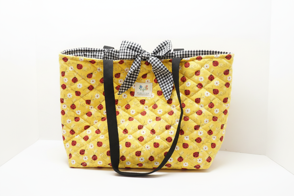 Yellow quilted tote bag with a checkered ribbon on a white background