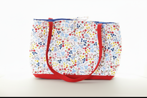 Floral-patterned tote bag with red handles on a white background