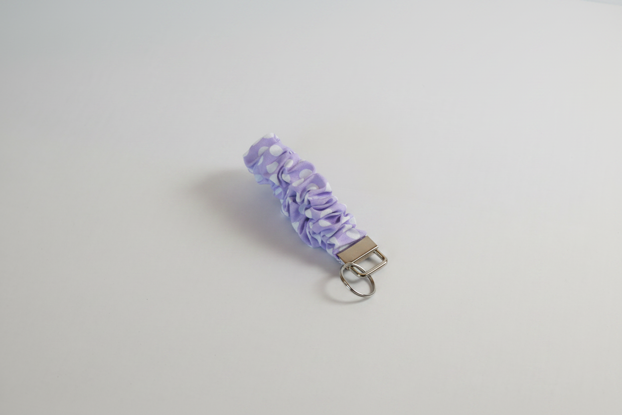 Purple scrunchie keychain on a light gray background