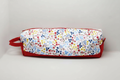 The Vibrant Floral Hot Tool & Travel Bag featuring a pink, purple, and amber botanical print on white cotton fabric, designed with vertical channel quilting, a gold top zipper with a matching fabric pull-tab, a side hand strap, and a centered white KIALIYAH label.