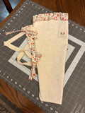 Texas Sunrose and Blossom Bouquet Wrap canvas flower carrier featuring a mottled cream canvas with red-orange floral ruffles and matching fabric side ties on a gray cutting mat.