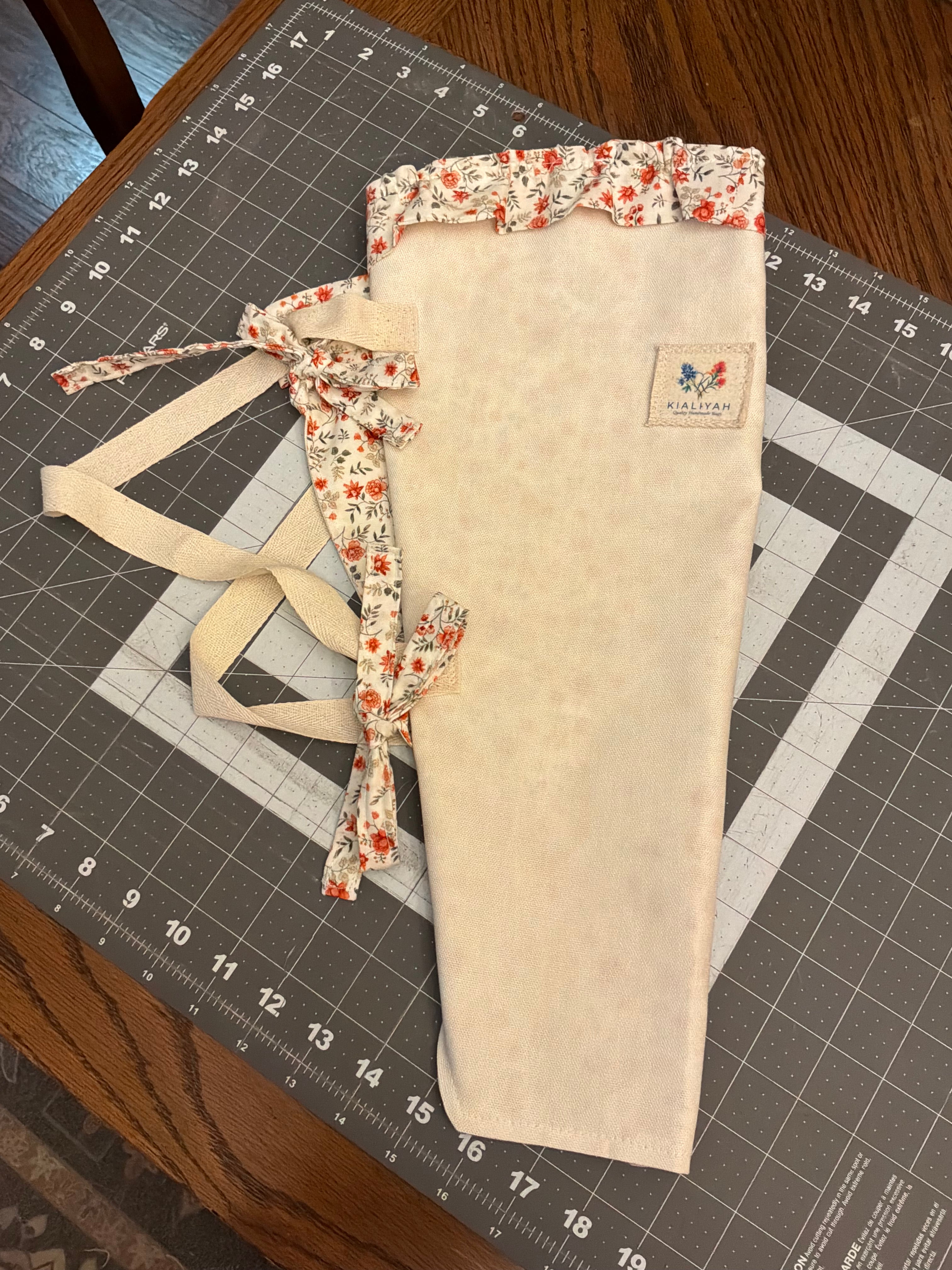 Texas Sunrose and Blossom Bouquet Wrap canvas flower carrier featuring a mottled cream canvas with red-orange floral ruffles and matching fabric side ties on a gray cutting mat.