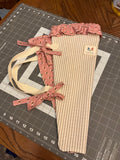 Prairie Stripe and Honeybee Bouquet Wrap canvas flower carrier featuring a warm neutral and cream ticking stripe pattern with a dusty rose honeybee ruffle top and matching bee-print side ties on a gray cutting mat.