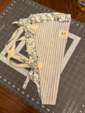 Coastal Bend Stripe and Blossom Bouquet Wrap canvas flower carrier featuring a slate-blue and cream ticking stripe canvas with light blue floral ruffles and matching fabric side ties on a gray cutting mat.