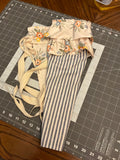 Concan Double-Ruffle and Stripe Bouquet Wrap canvas flower carrier featuring a classic navy and cream ticking stripe canvas base with a double layered ochre and peach floral print ruffle top and matching side ties on a gray cutting mat.