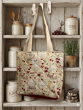 Bless the Baker Quilted Carryall canvas grocery bag featuring a cream kitchen print with rolling pins, chef hats, and red cherries, wide cream shoulder straps, and a central brand label hanging from a pantry shelf hook.