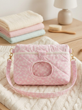 Pink Blossom Quilted Diaper Pouch showcasing a pastel pink ditsy floral print with diamond quilting, an integrated wipe window, a pink heart snap closure, and a matching shoulder strap on a knit blanket.