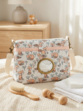 Fox and Fern Quilted Diaper Pouch showcasing an illustrated peach fox print with geometric trim, a brass-rimmed wipe window, and a snap closure flap resting on cloth diapers and a knit blanket in a nursery.