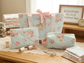 Pastel Rose and Polka Dot Quilted Travel Bundle featuring a matching light blue and pink rose canvas tote bag with a pink bow, a boxy cosmetic case, and a flat zipper pouch on a wooden table with lace runner.