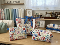 Cottage Garden Quilted Travel Bundle featuring a matching white watercolor wildflower canvas tote bag with a blue polka dot bow, a boxy cosmetic case, and a flat zipper pouch on a wooden table.
