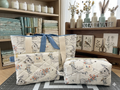 Bee Hive Quilted Travel Bundle featuring a matching cream canvas tote bag with a cornflower blue bow, a boxy cosmetic case, and a flat scripture zipper pouch on a cutting mat in a sewing studio.