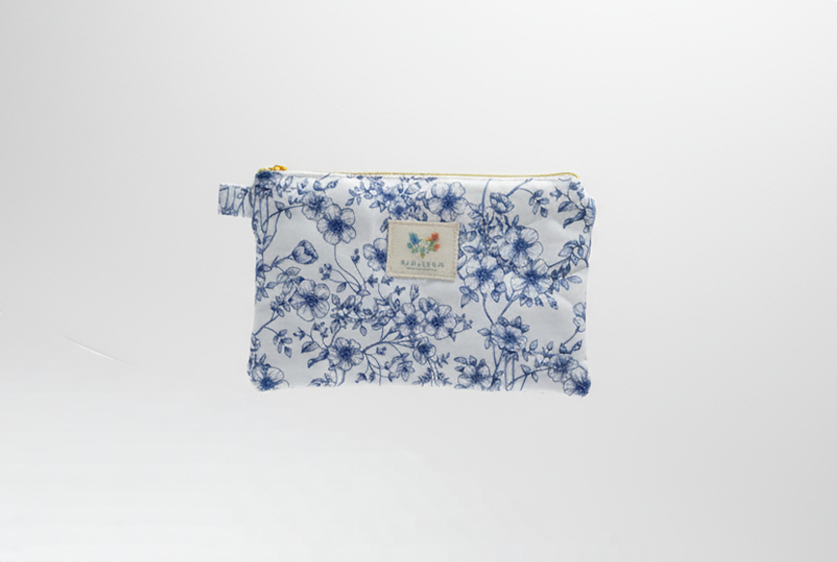 The Blue Toile Quilted Coin Pouch & Small Wallet featuring a monochrome blue pastoral toile print on cotton fabric, designed with vertical channel quilting, a gold-tone top zipper with a matching fabric pull-tab, and a centered white KIALIYAH label.