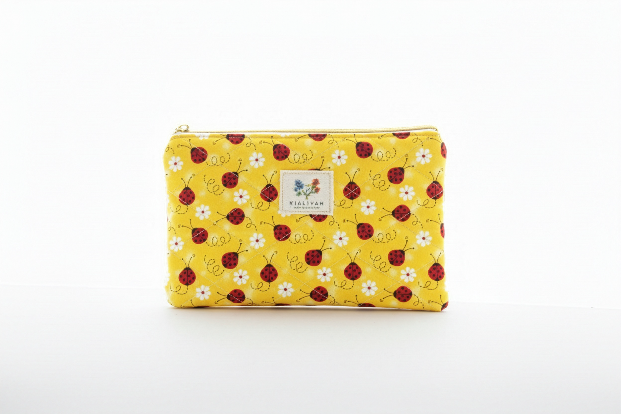 The Sunny Ladybug Quilted Pouch & Small Wallet featuring a botanical vine and ladybug top print, a yellow and white gingham check quilted base, a gold-tone top zipper with a matching fabric pull-tab, and a centered white KIALIYAH label.