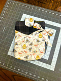 Handcrafted dark plaid tablet sleeve featuring a cream front pocket with honeybees, honeycombs, a decorative side bow tie, and a matching snap closure tab on a cutting mat.