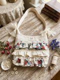 Vintage Rose Tiered Ruffle Purse showcasing a handmade cream shoulder bag with alternating tiers of red and blue rose print ruffles, detailed with wide eyelet lace borders and two large lace bows on a rustic wooden table.